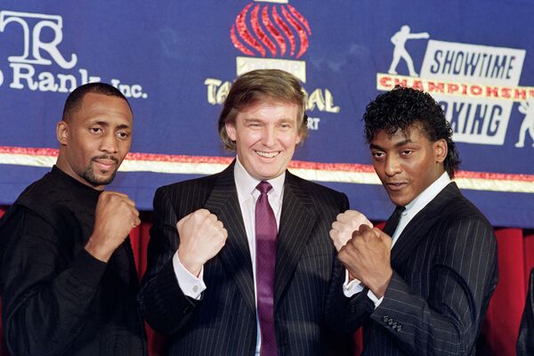 Le milliardaire Donald Trump (au centre), qui a fait une fortune dans l’immobilier, lève les poings le 15 février 1990 à New-York lors de l’annonce d’un combat entre Thomas « The Hitman » Hearns (à gauche) et Michael « The Silk » Olajide (à droite), qui se déroulera le 28 avril 1990 au Trump Taj Mahal Casino d’Atlantic City. - Sputnik Afrique