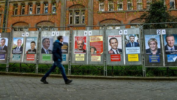 A man walks past campaign posters of the eleven candidates running for the French presidential election in Lille on April 10, 2017. - Sputnik Afrique
