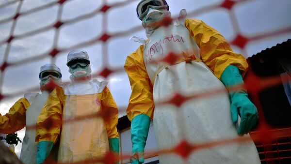 A file picture taken on August 14, 2014 shows Medecins Sans Frontieres (MSF) medical staff wearing protective clothing treating the body of an Ebola victim at their facility in Kailahun. - Sputnik Afrique