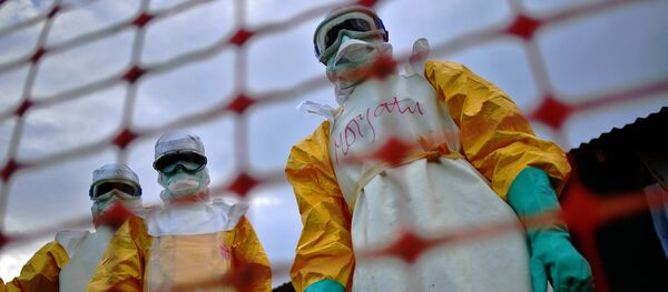 A file picture taken on August 14, 2014 shows Medecins Sans Frontieres (MSF) medical staff wearing protective clothing treating the body of an Ebola victim at their facility in Kailahun. - Sputnik Afrique