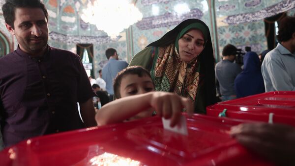 An Iranian boy casts his mother's ballot for the presidential elections at a polling station in Tehran on May 19, 2017 - Sputnik Afrique