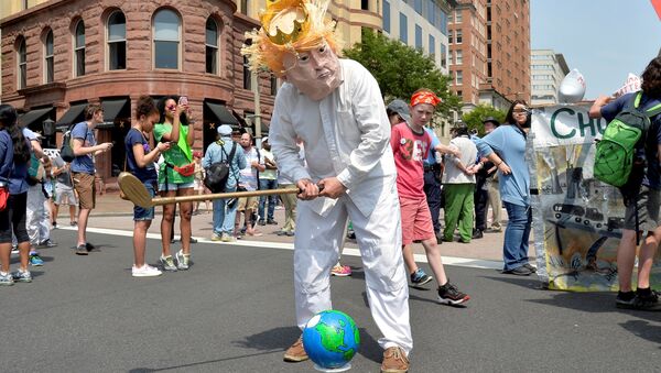 A protester in a costume depicting Trump sets an Earth on a tee as he holds a golf club while joining demonstrators moving down Pennsylvania Avenue during a People's Climate March, to protest U.S. President Donald Trump's stance on the environment, in Washington, U.S., April 29, 2017. - Sputnik Afrique