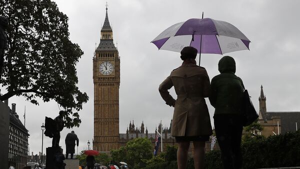 People shelter from the rain beneath an umbrella as they observe a minutes' silence near the Elizabeth Tower, commonly referred to as Big Ben, at the Houses of Parliament in London on June 6, 2017, in memory of the victims of the June 3 terror attacks. - Sputnik Afrique