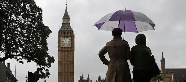 People shelter from the rain beneath an umbrella as they observe a minutes' silence near the Elizabeth Tower, commonly referred to as Big Ben, at the Houses of Parliament in London on June 6, 2017, in memory of the victims of the June 3 terror attacks. - Sputnik Afrique