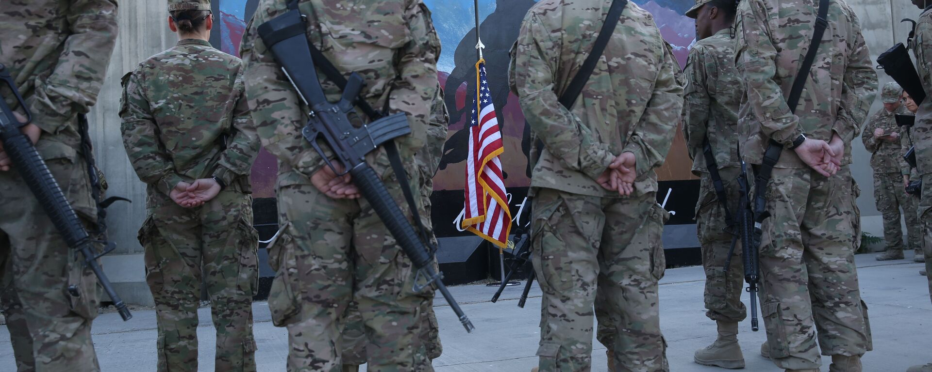 Des membres des services américains se tiennent devant un drapeau américain lors d'une cérémonie à l'occasion du treizième anniversaire des attaques terroristes du 11 septembre 2001 devant le mémorial du World Trade Center à l'aérodrome de Bagram, en Afghanistan, jeudi 11 septembre 2014. - Sputnik Afrique, 1920, 16.08.2021