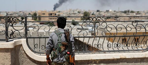 A Kurdish fighter from the People's Protection Units (YPG) looks at a smoke after an coalition airstrike in Raqqa, Syria June 16, 2017 - Sputnik Afrique