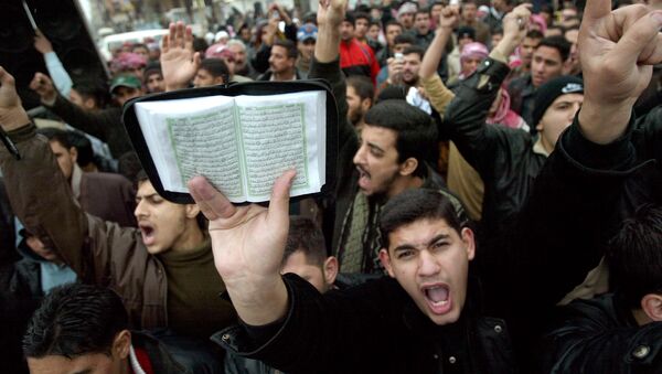 Hundreds of Muslim worshippers gather after Friday prayers hold a copy of the holy Qur'an and shout slogans denouncing Denmark for publishing cartoons of the Prophet Muhammad in 2005, at the revered Abu Hanifa Mosque, Friday, Feb. 3, 2006, in Baghdad, Iraq. - Sputnik Afrique