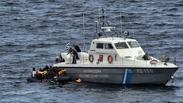 Hellenic coast guard personnel rescue refugees and migrants on a dinghy as they try to reach the Greek island of Lesbos while crossing the Aegean sea from Turkey on September 29, 2015 - Sputnik Afrique