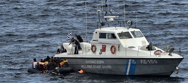 Hellenic coast guard personnel rescue refugees and migrants on a dinghy as they try to reach the Greek island of Lesbos while crossing the Aegean sea from Turkey on September 29, 2015 - Sputnik Afrique