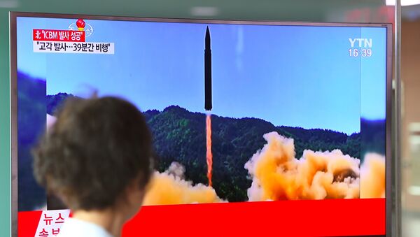 A woman walks past a television screen showing a picture of North Korea's launch of an intercontinental ballistic missile (ICBM), at a railway station in Seoul on July 4, 2017. - Sputnik Afrique