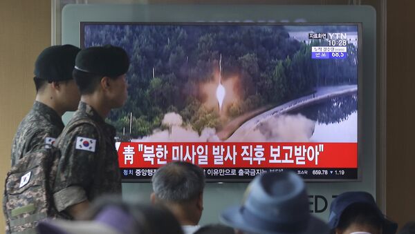 Army soldiers walk by a TV news program showing a file image of a missile being test-launched by North Korea at the Seoul Railway Station in Seoul, South Korea, Tuesday, July 4, 2017. - Sputnik Afrique