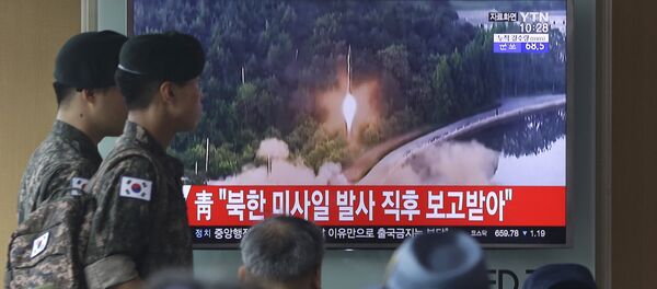 Army soldiers walk by a TV news program showing a file image of a missile being test-launched by North Korea at the Seoul Railway Station in Seoul, South Korea, Tuesday, July 4, 2017. - Sputnik Afrique