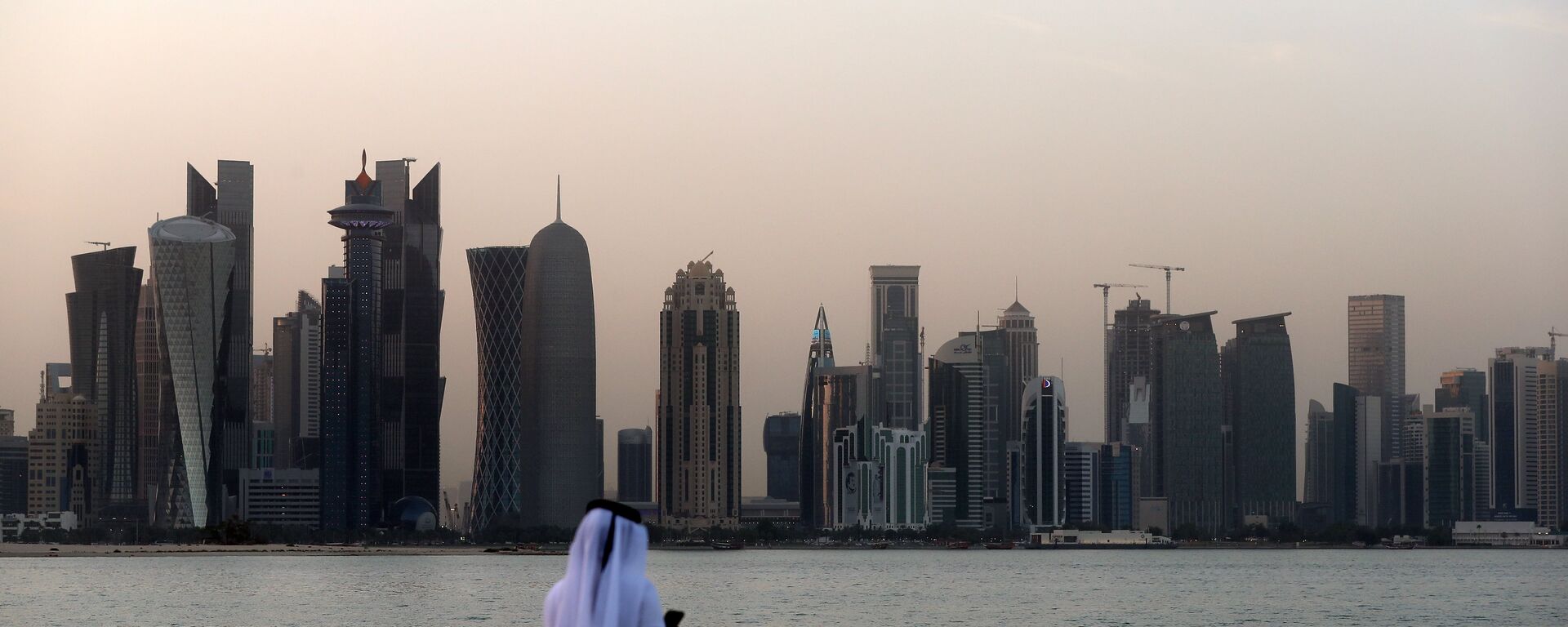 A man looks at his phone on the corniche in the Qatari capital Doha on July 2, 2017. - Sputnik Afrique, 1920, 24.11.2021