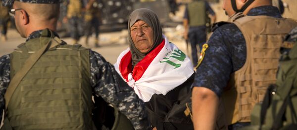 An elderly woman draped in Iraq's na tional flag looks on as she stands by Iraq's federal police members celebrating in the Old City of Mosul on July 9, 2017 after the government's announcement of the liberation of the embattled city. - Sputnik Afrique