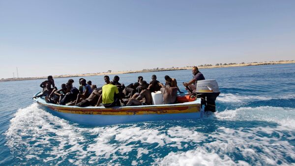 Migrants ride in a boat after they were rescued by Libyan coastguard off the coast of Gharaboli, east of Tripoli, Libya July 8, 2017 - Sputnik Afrique
