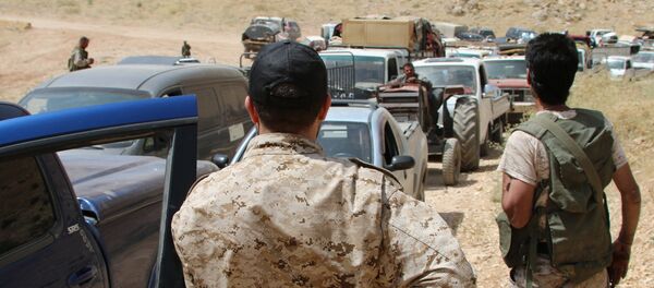 Armed men stand guard as a convoy of Syrian refugees leaves the Lebanese eastern border town of Arsal heading towards the Syrian region of Qalamoun on July 12, 2017 as part of a deal that was negotiated by Syrian rebels in the camps and Lebanon's Hezbollah group. Armed men stand guard as a convoy of Syrian refugees leaves the Lebanese eastern border town of Arsal heading towards the Syrian region of Qalamoun on July 12, 2017 as part of a deal that was negotiated by Syrian rebels in the camps and Lebanon's Hezbollah group. - Sputnik Afrique