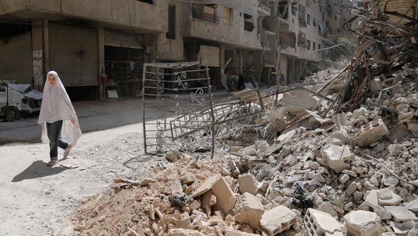 A girl walks past the rubble of a destroyed building down a street in the rebel-held Syrian town of Ayn Tarma, in the Ghouta area east of the capital Damascus on July 19, 2017. - Sputnik Afrique