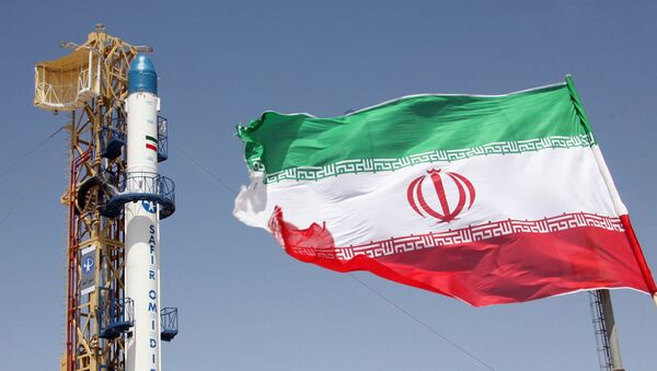 Iranian flag fluttering in front of Iran's Safir Omid rocket, which is capable of carrying a satellite into orbit, before it's launch in a space station at an undisclosed location in the Islamic republic - Sputnik Afrique