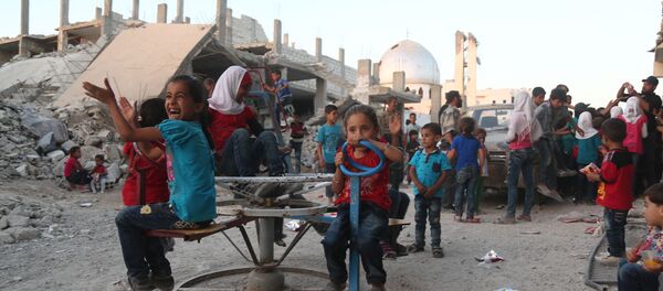 Syrian children, who fled their homes in Ghouta's al-Marj town, play amidst the debris of buildings in the town of al-Nashabiyah in the eastern Ghouta region, a rebel stronghold east of the capital Damascus on June 27, 2017. - Sputnik Afrique