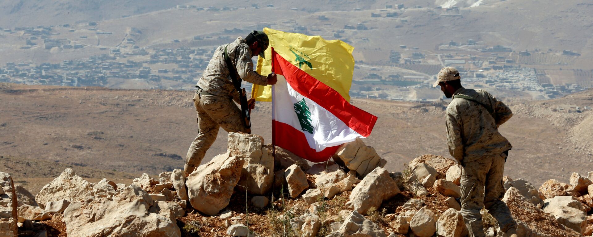 Des combattants du Hezbollah mettent des drapeaux libanais et du Hezbollah à Juroud Arsal, à la frontière syro-libanaise, le 25 juillet 2017. - Sputnik Afrique, 1920, 27.04.2021