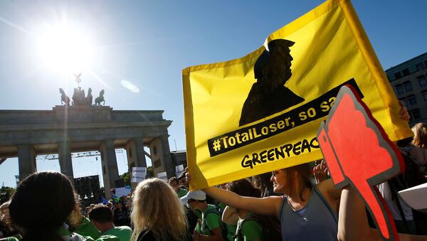 Les gens tiennent des bannières alors qu'ils protestent près de la Porte de Brandebourg, à côté de l'ambassade des États-Unis, contre le retrait des États-Unis de l'accord de Paris sur le changement climatique, à Berlin, en Allemagne, le 2 juin 2017 - Sputnik Afrique