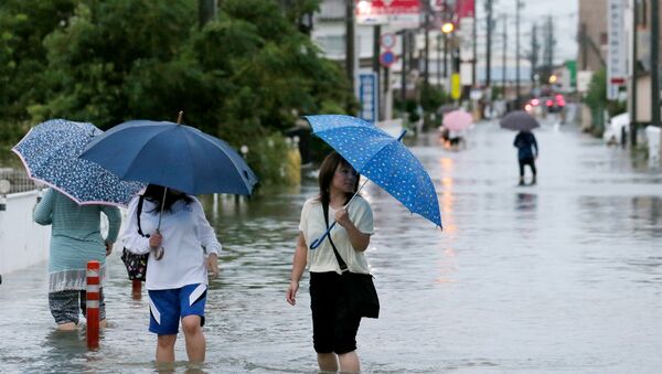 Pedestrians wade through flood waters on a road following torrential rains brought on by Typhoon Etau in Hamamatsu, Shizuoka prefecture, central Japan on September 8, 2015 - Sputnik Afrique