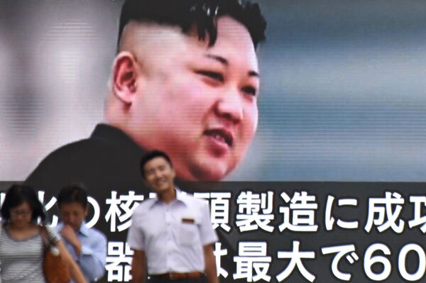Des gens passant devant un écran géant montrant le dirigeant nord-coréen Kim Jong-un à Tokyo, au Japon - Sputnik Afrique