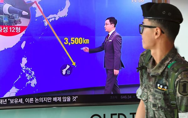 Un soldat sud-coréen passe devant un écran de télé avec une infographie montrant la distance entre la Corée du Nord et Guam, dans une gare à Séoul, le 9 août 2017 - Sputnik Afrique