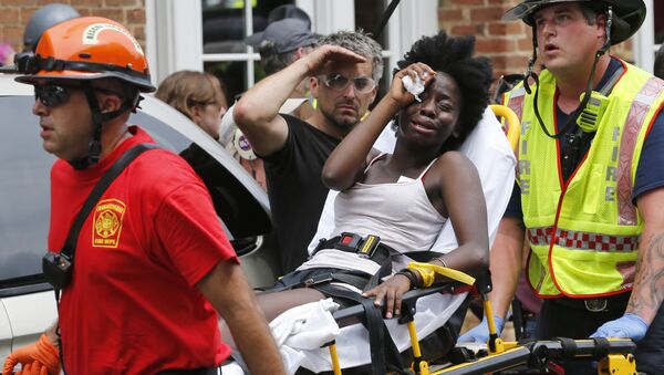Rescue personnel help an injured woman after a car ran into a large group of protesters after an white nationalist rally in Charlottesville, Va., Saturday, Aug. 12, 2017. - Sputnik Afrique