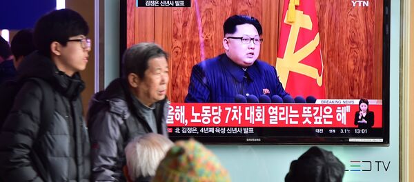 Commuters walk past a television screen showing a broadcast of North Korean leader Kim Jong-Un's New Year speech, at a railroad station in Seoul on January 1, 2016 - Sputnik Afrique