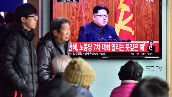 Commuters walk past a television screen showing a broadcast of North Korean leader Kim Jong-Un's New Year speech, at a railroad station in Seoul on January 1, 2016 - Sputnik Afrique