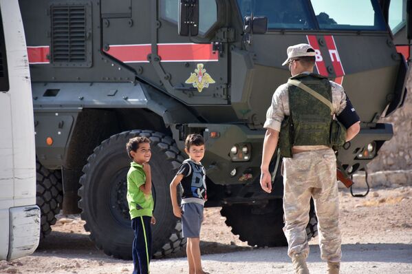Des enfants syriens et un agent de la police militaire russe à la périphérie d’Alep - Sputnik Afrique