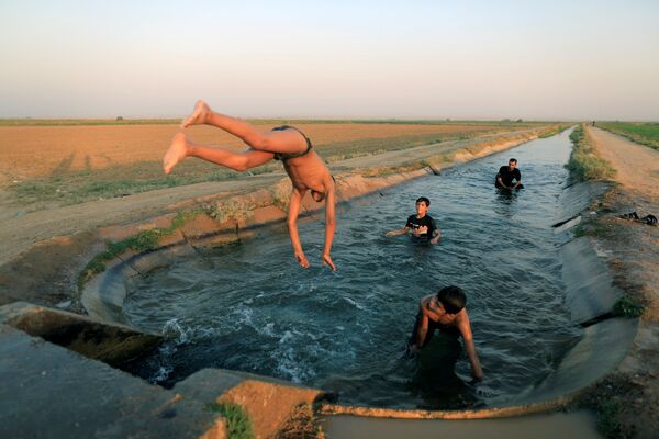 Des enfants se baignent dans un canal d’irrigation à la périphérie de Raqqa, en Syrie - Sputnik Afrique
