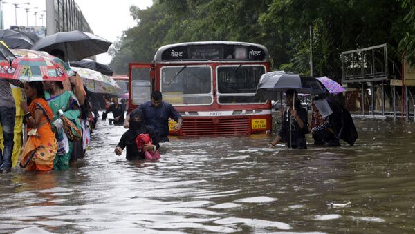 People walk through a waterlogged street following heavy rains in Mumbai, India - Sputnik Afrique