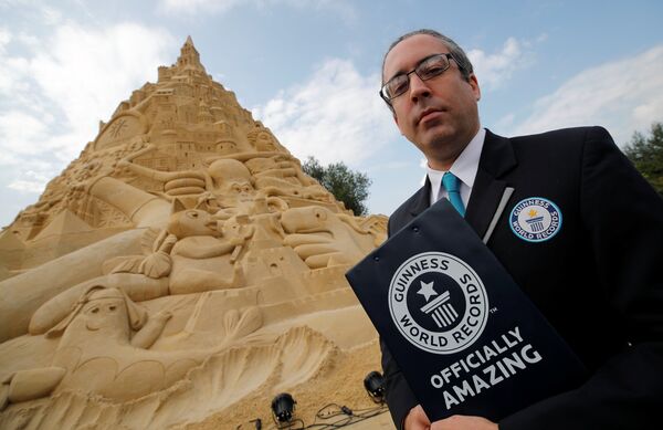 Jack Brockbank, the official judge of Guinness World Records stands next to the world's highest sandcastle (16.68 metres) in Duisburg, western Germany, September 1, 2017.  - Sputnik Afrique