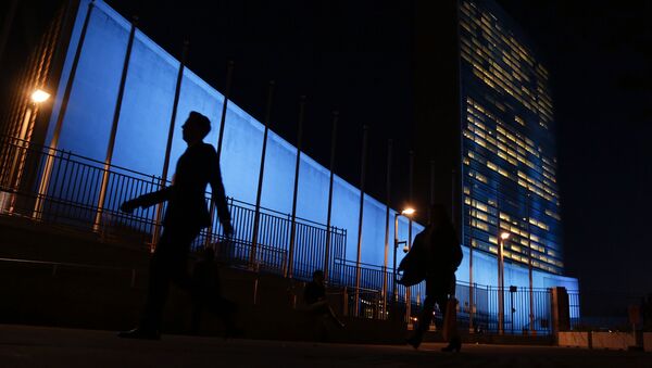Pedestrians walk by United Nations Headquarters, lit up in blue light, a day in advance of the 70th Anniversary of the U.N., Friday, Oct. 23, 2015, in New York - Sputnik Afrique
