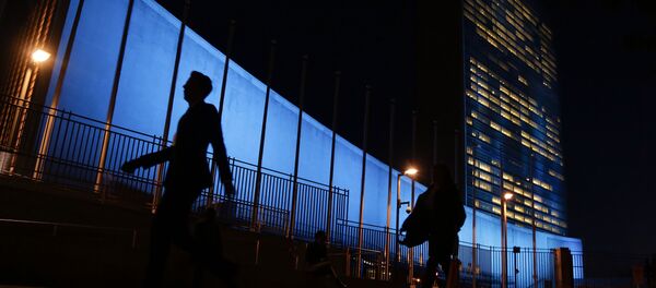 Pedestrians walk by United Nations Headquarters, lit up in blue light, a day in advance of the 70th Anniversary of the U.N., Friday, Oct. 23, 2015, in New York - Sputnik Afrique