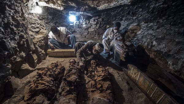 A picture taken on September 9, 2017 shows Egyptian labourers and archaeologists unearthing mummies at a newly-uncovered ancient tomb for a goldsmith dedicated to the ancient Egyptian god Amun, in the Draa Abul Naga necropolis on the west bank of the ancient city of Luxor, which boasts ancient Egyptian temples and burial grounds. - Sputnik Afrique
