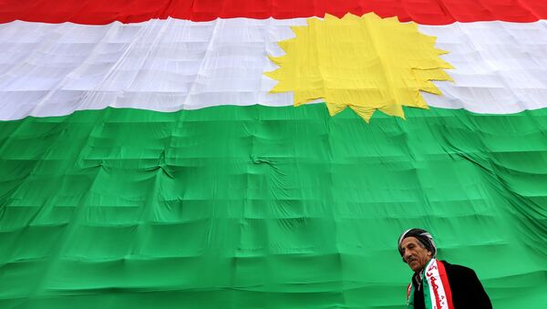 An Iraqi Kurdish man walks past a giant flag of Kurdistan as Kurds marked Flag Day on December 17, 2015 in Arbil, the capital of the autonomous Kurdish region in northern Iraq. - Sputnik Afrique