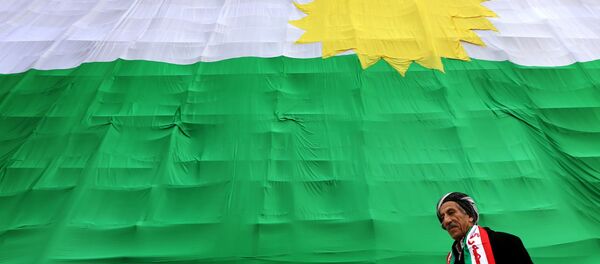 An Iraqi Kurdish man walks past a giant flag of Kurdistan as Kurds marked Flag Day on December 17, 2015 in Arbil, the capital of the autonomous Kurdish region in northern Iraq. - Sputnik Afrique