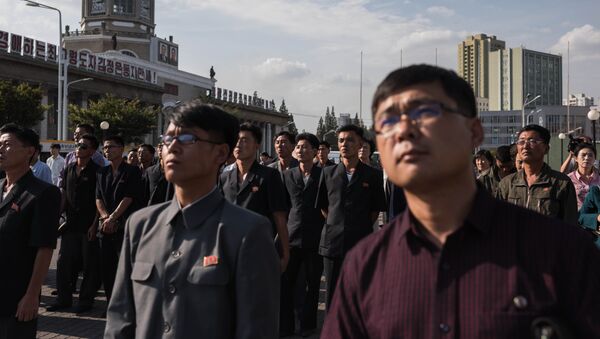 Spectators listen to a television news brodcast of a statement by North Korean leader Kim Jong-Un, before a public television screen outside the central railway station in Pyongyang on September 22, 2017 - Sputnik Afrique