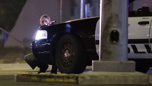A police officer takes cover behind a police vehicle during a shooting near the Mandalay Bay resort and casino on the Las Vegas Strip, Sunday, Oct. 1, 2017, in Las Vegas - Sputnik Afrique