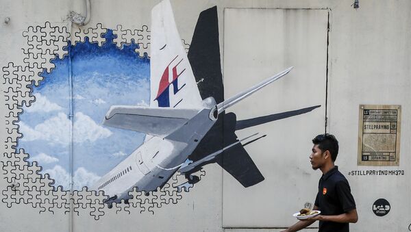 In this Tuesday, Feb. 23, 2016, file photo, a waiter walks past a mural of flight MH370 in Shah Alam outside Kuala Lumpur, Malaysia. - Sputnik Afrique