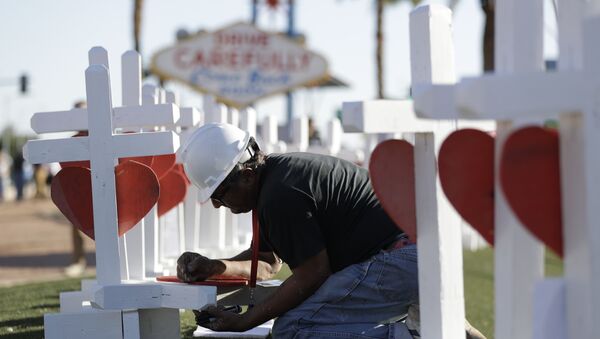 Greg Zanis writes the name of a victim of Sunday's mass shooting as he places crosses near the city's famous sign Thursday, Oct. 5, 2017, in Las Vegas. - Sputnik Afrique
