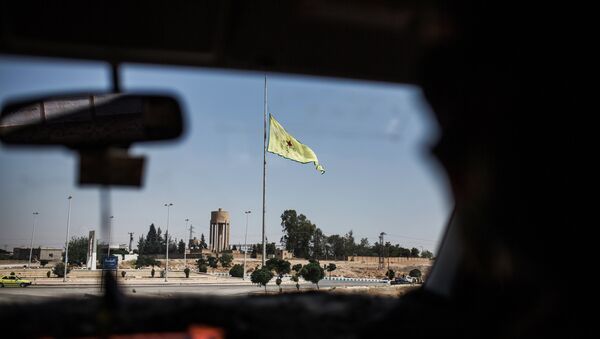 A Kurdish People's Protection Units (YPG) flag is seen through a car window on June 22, 2015, in the northern Syrian town of Tal Abyad on the border with Turkey, in Syria's Raqqa governorate. - Sputnik Afrique