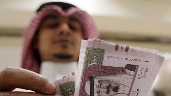 A Saudi banker counts new one hundred riyals bearing the portrait of Saudi King Abdullah bin Abdul Aziz al-Saud at a bank in Riyadh, 05 June 2007. - Sputnik Afrique