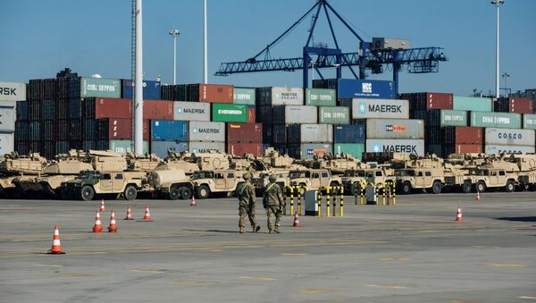 Soldiers walk near U.S. military equipment which arrived as part of NATO mission at port in Gdansk, Poland - Sputnik Afrique