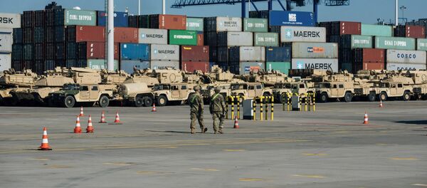 Soldiers walk near U.S. military equipment which arrived as part of NATO mission at port in Gdansk, Poland - Sputnik Afrique