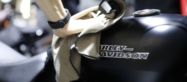 Мужчина протирает поверхность мотоцикла Harley Davidson на международной выставке мотоспорта EICMA MOTO в Милане - Sputnik Afrique