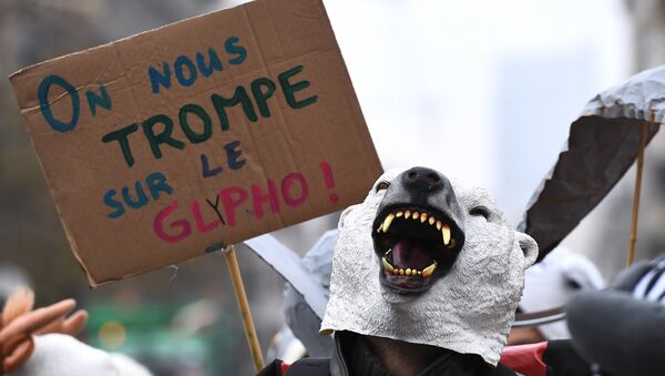 An activist from E.Z.L.N - Ensemble Zoologique de Liberation de la Nature (Zoological Ensemble for Nature's Liberation) holds a cardboard reading we are being deceived (on Glyphosate's safety) during a demonstration against the weed-killer glyphosate and US agrochimical company Monsanto in front of the Justice Palace in Brussels where nine of their activists are facing justice after an action against pesticide, on November 9, 2017. - Sputnik Afrique